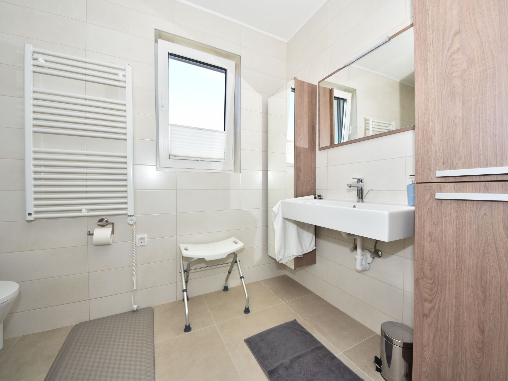 Une salle de bain moderne équipée de toilettes, d’un bidet, d’un lavabo et d’une petite fenêtre.