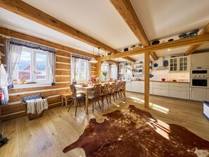 A rustic cabin interior with a dining area, wooden beams, a large fur rug, and a kitchen with white cabinets. - Charming Mountain Lodge & Wellness by Interhome (Horní Maršov/Pec pod Sněžkou)