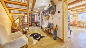 A cozy room with a wooden ceiling, a cowhide rug, a chair, a table, and a hanging basket. - Charming Mountain Lodge & Wellness by Interhome (Horní Maršov/Pec pod Sněžkou)