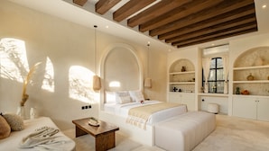 A spacious bedroom with a large bed, a sitting area, and built-in shelving with decorative items. - Romantic Villa - Ultimate Love Sanctuary (Canggu)