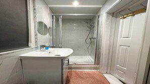 A modern bathroom with a glass shower enclosure, a white sink, and a mirror.