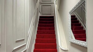 A staircase with red carpeted steps and white walls.