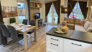 Un salon moderne et bien éclairé, comprenant une table à manger, des chaises, un canapé et un téléviseur.