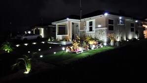 Una moderna casa a due piani con un vialetto ben illuminato e un giardino.