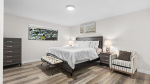 A bedroom with a bed, nightstands, a dresser, a window with a view of trees, and a painting on the wall. - Cozy 3-bedroom house in peaceful Renton with WiFi, AC (Renton)