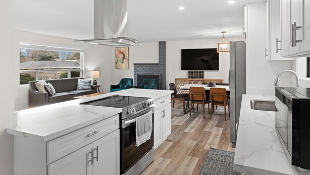 A modern kitchen with white cabinetry, a built-in oven, and a large island with a stovetop. - Cozy 3-bedroom house in peaceful Renton with WiFi, AC (Renton)