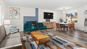 A modern living room with a sofa, teal armchairs, a wooden coffee table, and a fireplace. - Cozy 3-bedroom house in peaceful Renton with WiFi, AC (Renton)