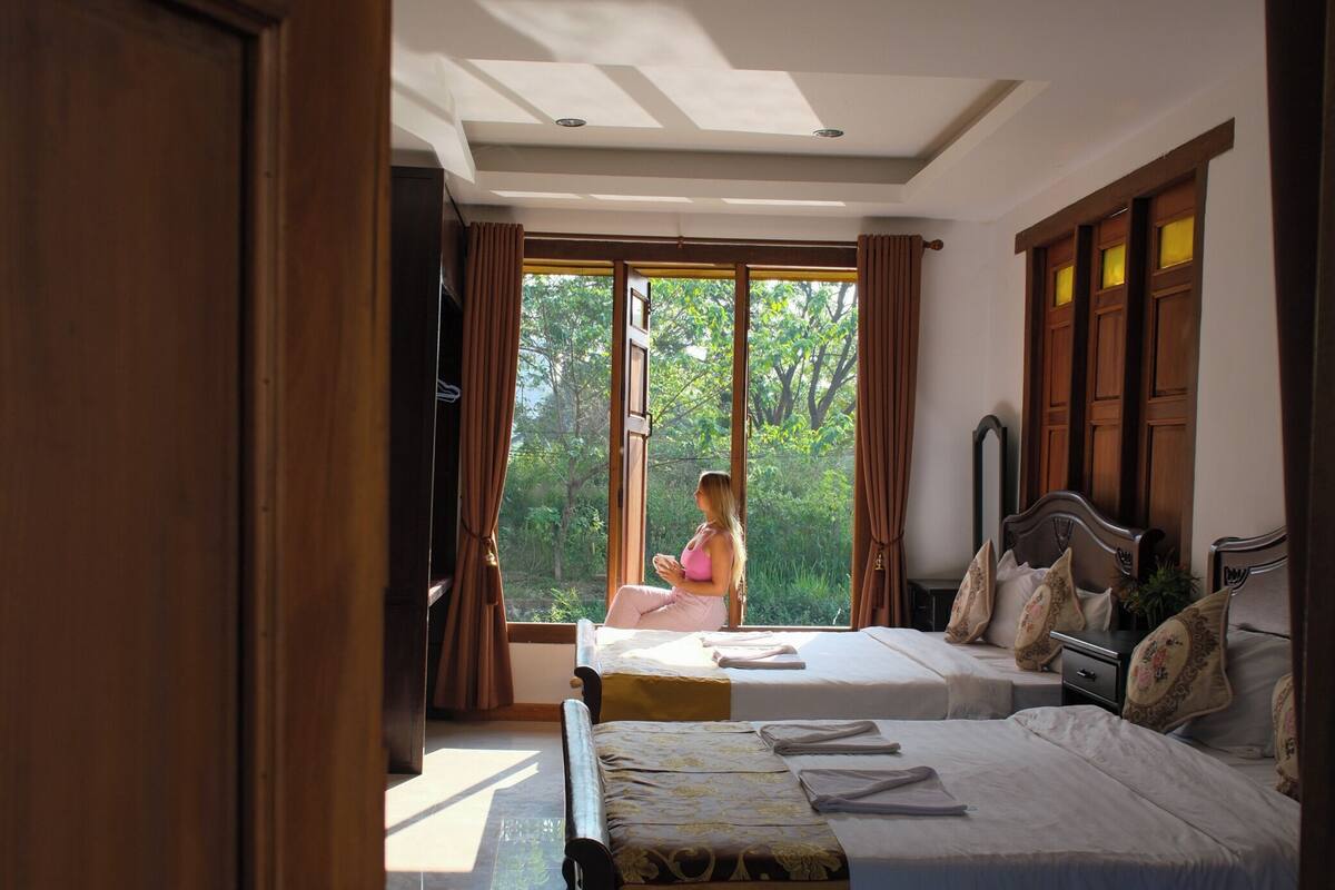 A bedroom with two beds, a large window, and a view of the outdoors.