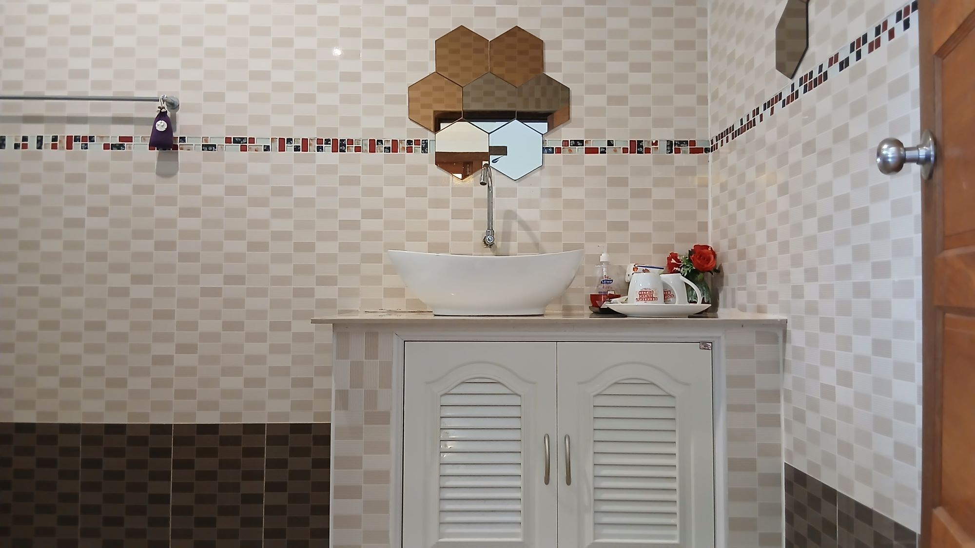 Een badkamer met een witte wastafel, een spiegel en een handdoekhouder.