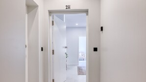 A hallway with a door labeled "2H" leading to a room with a white sofa and a rug. - Beco Santa Emilia 2H, a Home in Madeira (Funchal)