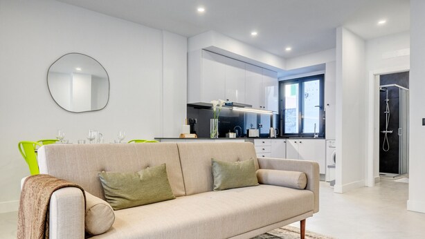 A modern living room with a beige sofa, a green chair, and a large mirror on the wall. - Beco Santa Emilia 2H, a Home in Madeira (Funchal)