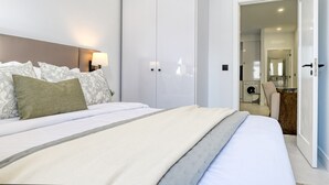 A modern bedroom with a large bed, a nightstand, a wall-mounted lamp, and a wardrobe. - Beco Santa Emilia 2H, a Home in Madeira (Funchal)