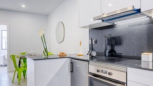 A modern kitchen with a built-in oven, a stainless steel range hood, and a black stovetop. - Beco Santa Emilia 2H, a Home in Madeira (Funchal)