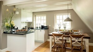 Una cocina con una isla central, sillas de madera y una mesa de comedor para cuatro.