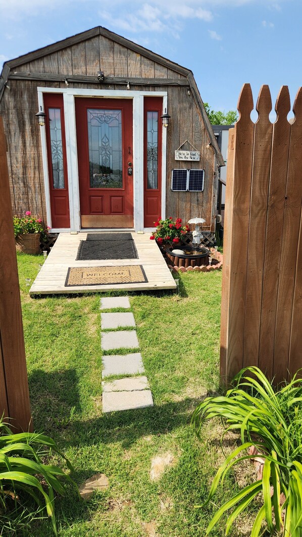 A wooden barn with a red door and a welcome mat. - Cozy cabin on a working horse rescue with WiFi, HVAC, plumbed outhouse, shower (Coweta)