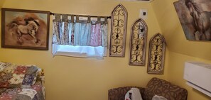 Une pièce avec un canapé à motifs floraux, une fenêtre ornée de rideaux à motifs et deux panneaux décoratifs fixés au mur.