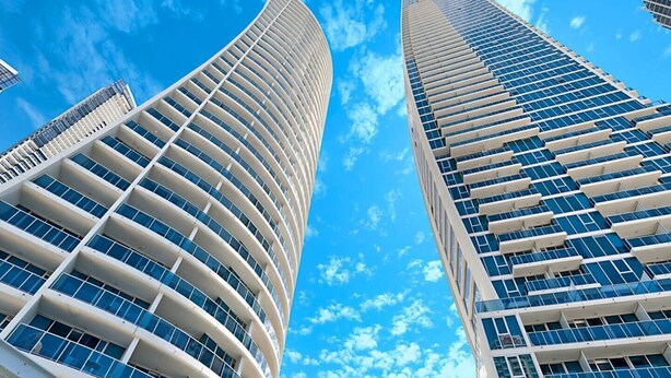 Dois edifícios altos com fachadas curvas e grandes janelas, provavelmente parte de um desenvolvimento urbano moderno.