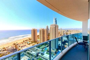 A balcony with a clear view of a beach and cityscape, including tall buildings and a swimming pool.