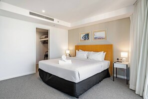 A hotel room with a large bed, bedside tables with lamps, a closet, and two framed pictures on the wall.
