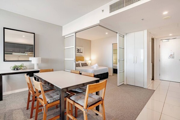 A modern hotel room with a dining area, a bed, and a wardrobe.