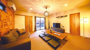 A modern living room with a sofa, a dining table, and a TV. - Ishigaki sen (Beppu)