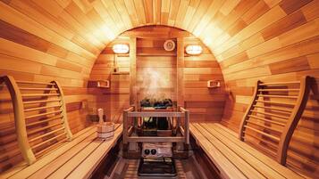 A sauna with wooden walls and benches, a bench heater, and a steam shower.