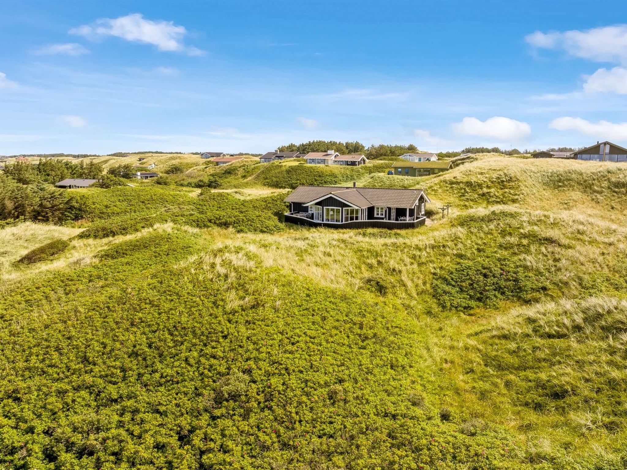 A house on a grassy hill with a clear sky.