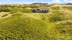 Une maison située sur une colline verdoyante, sous un ciel dégagé.
