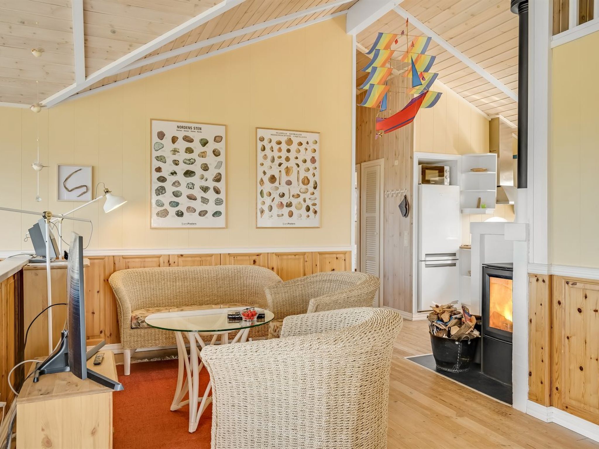 A cozy room with a fireplace, wicker furniture, and two framed pictures of stones.