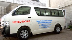 Un fourgon blanc avec l’inscription « HÔTEL KINYAO » et les coordonnées de l’établissement sur le côté.