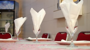 Une table à manger recouverte d’une nappe à motifs floraux, avec des serviettes blanches dans des porte-serviettes en verre.