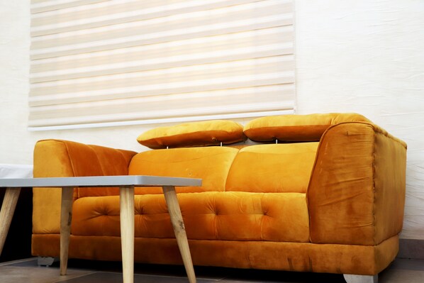 A mustard-colored sofa with wooden legs and a small table in front. - Hotel Kinyao (Parakou)