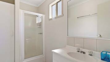 Un baño con ducha, lavabo y espejo.