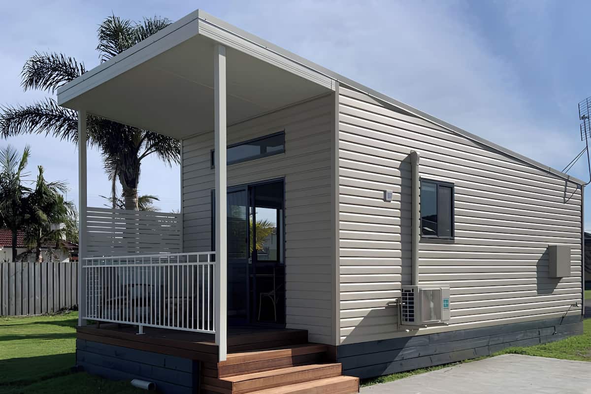 Een modern gelijkvloers huis met een overdekte veranda, een kleine voortuin en een heldere lucht.