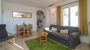 A living room with a grey sofa, a wooden dining table, and a green rug. - Tetuan 7 - El Oasis de Capistrano! (Nerja)