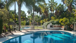 A swimming pool surrounded by palm trees and a white fence. - Tetuan 7 - El Oasis de Capistrano! (Nerja)