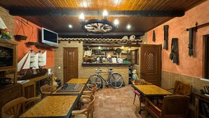 A rustic interior with wooden tables and chairs, a bicycle, and a brick wall. - Quinta Jardim das Palmeiras, T2 nº3, Algoz (Silves)