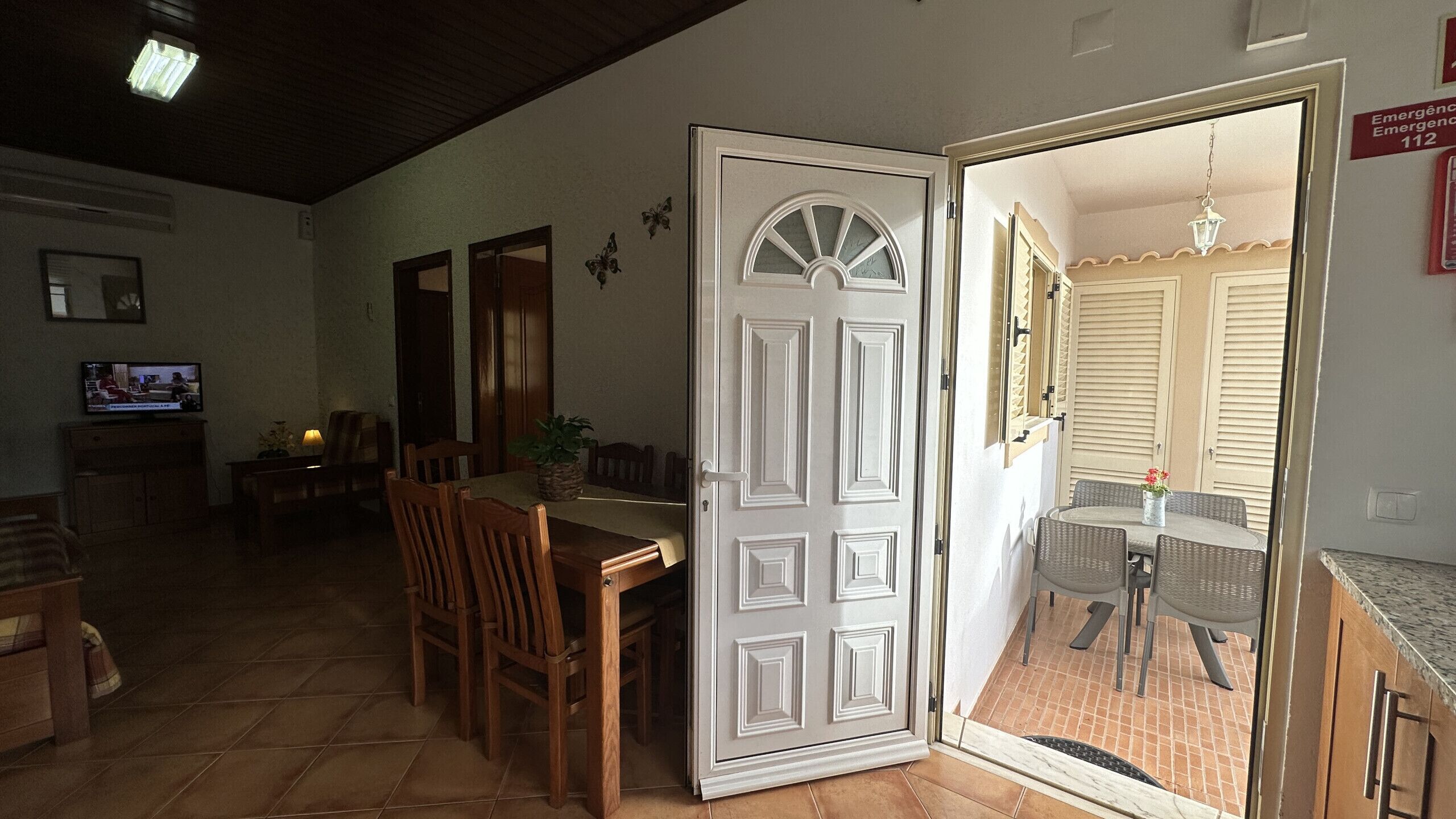 A dining area with a table and chairs, a television, and a door leading to an outdoor patio.