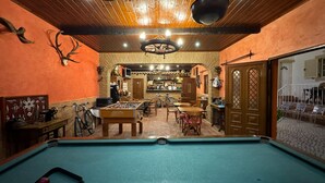 A cozy bar area with a pool table, wooden furniture, and a rustic decor including antlers and a vintage bicycle.