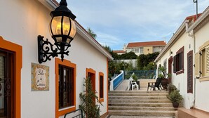 Une rue pavée avec un banc, un lampadaire et un escalier menant à un immeuble.