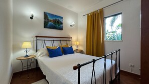 Classic design bedroom with a large bed, bedside tables, and a painting of a mountainous landscape.