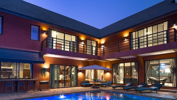 Ein zweistöckiges Haus mit Swimmingpool, Außenbereich zum Sitzen und einer Bar.