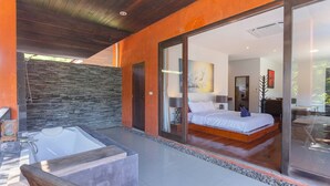 Ein modernes Schlafzimmer mit einem großen Bett, einer Glastür, die zu einem Balkon führt, und einer Steinwand.