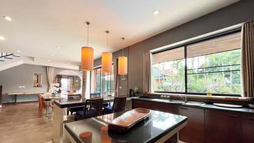 Una cocina moderna con un ventanal grande, luces colgantes y una zona de comedor con banco.