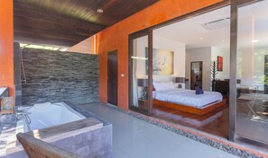 Quarto moderno com uma cama grande, uma porta de vidro para uma varanda e uma parede de pedra.
