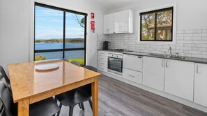 Une cuisine moderne avec des meubles blancs, une table à manger en bois et une vue sur un lac.