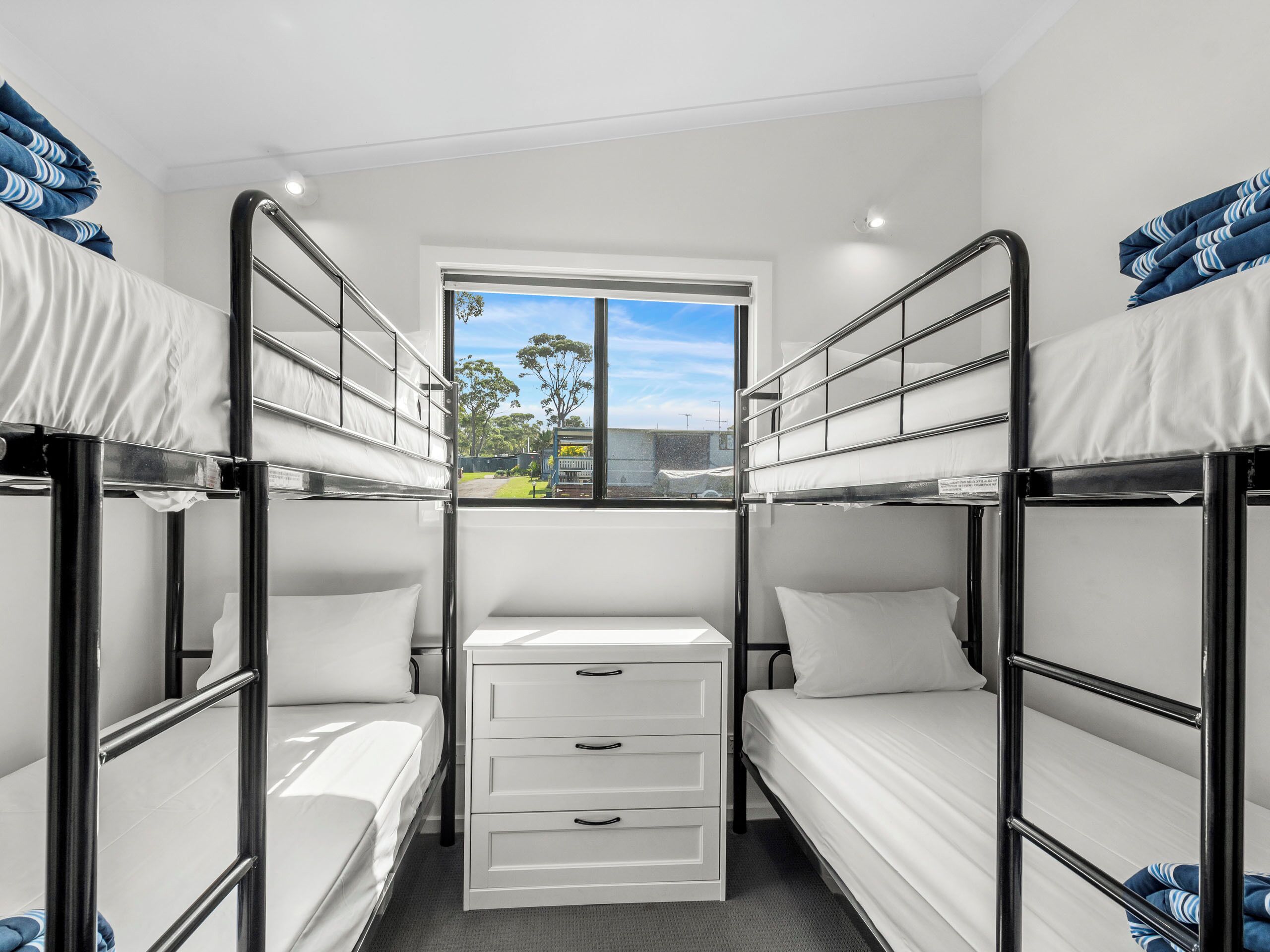 Un dormitorio con literas, una ventana y un aparador blanco.