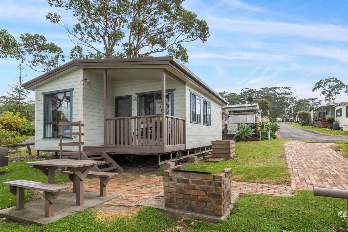 A small, single-story mobile home with a porch and a brick fireplace.