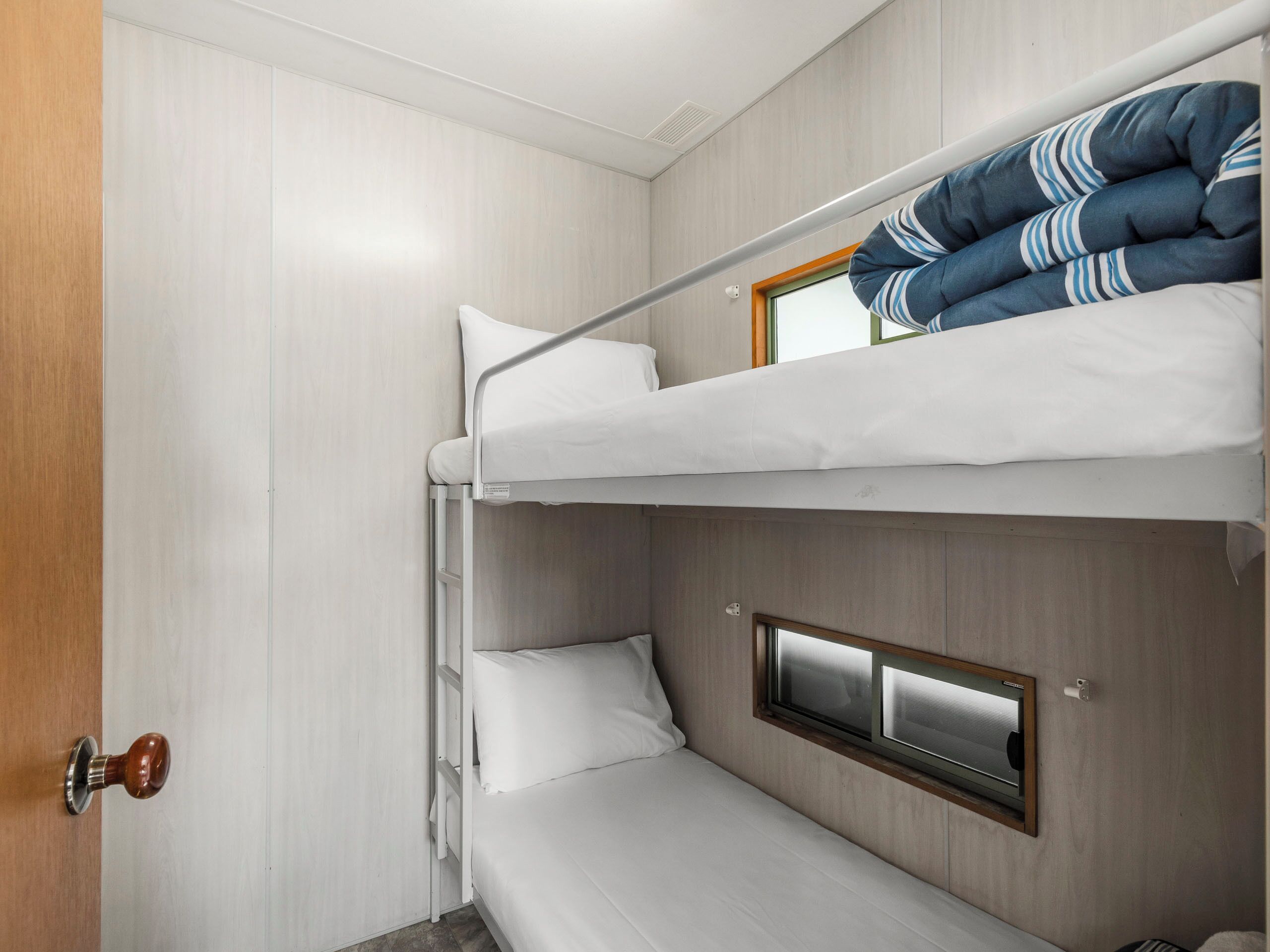 Une chambre avec un lit superposé, une fenêtre et une porte.
