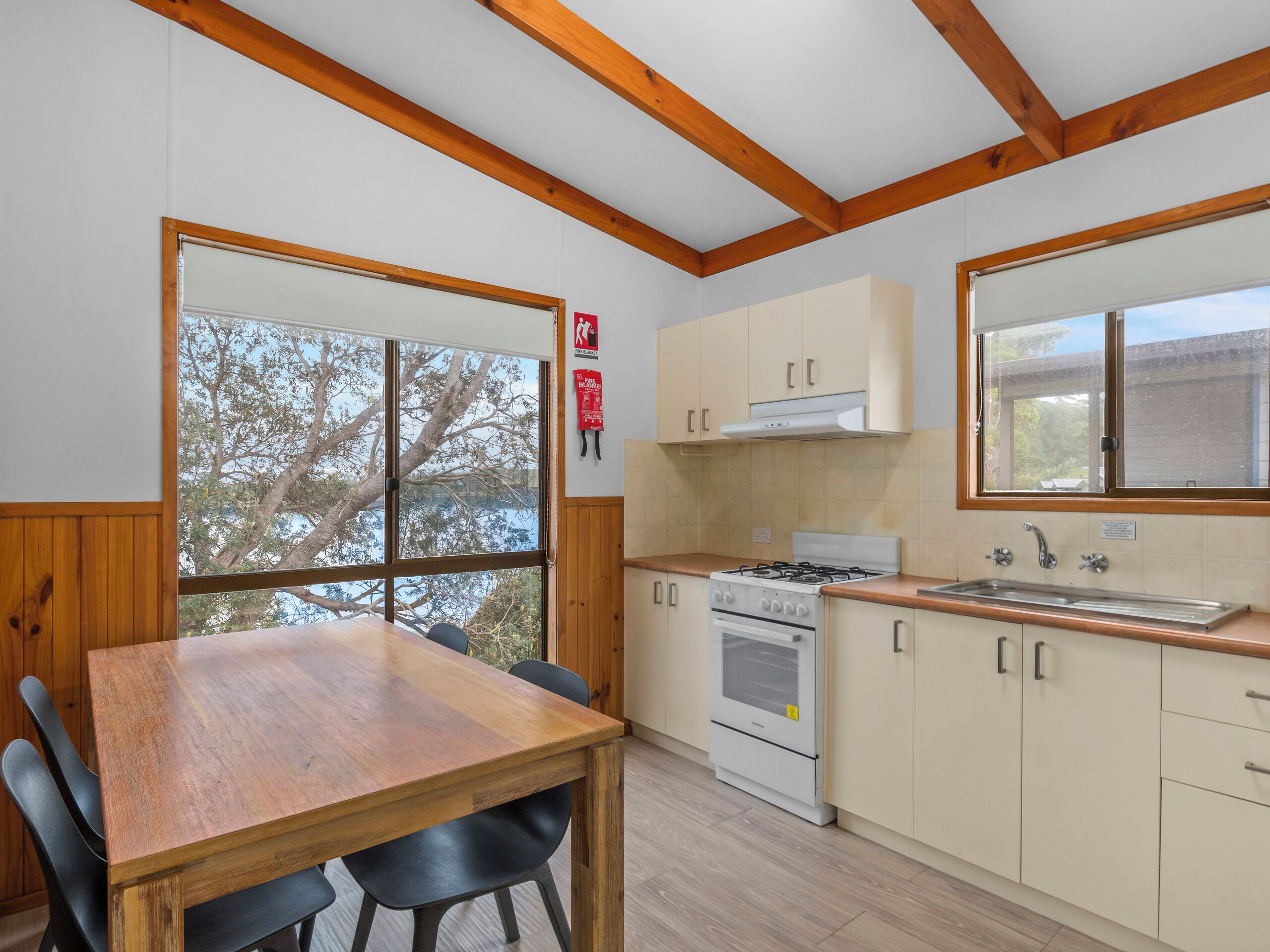 Een moderne keuken met houten balken, een groot raam en een eethoek met een houten tafel en stoelen.